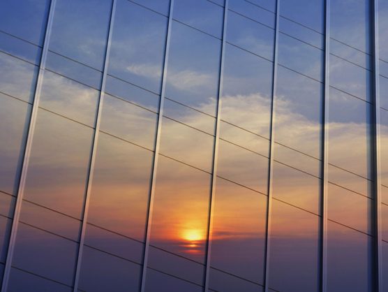 Sonnenuntergang spiegelt sich in Glasfassade von Bürogebäude