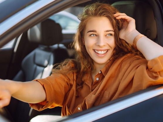 Lächelnde, junge Frau fährt Auto