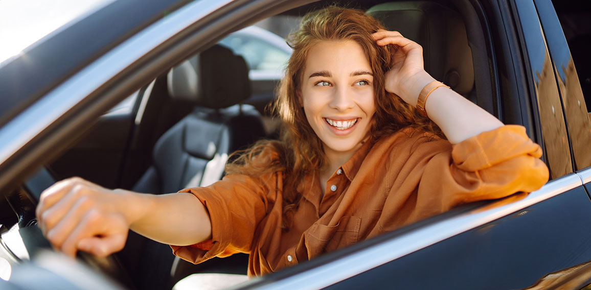 Lächelnde, junge Frau fährt Auto