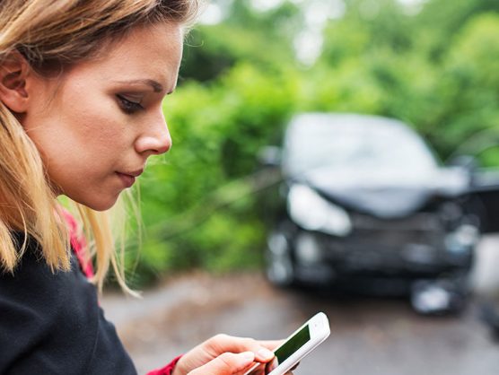 Frau bedient Smartphone nach Autounfall