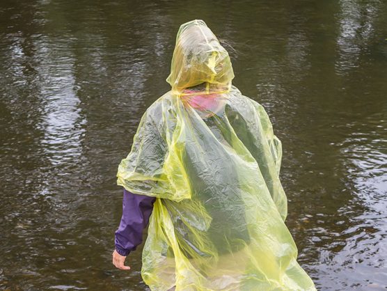 Frau mit Regenmantel in Hochwasser