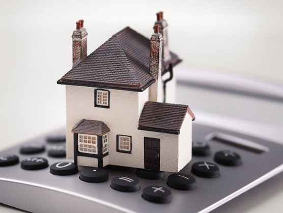 Miniaturhaus steht auf Taschenrechner
