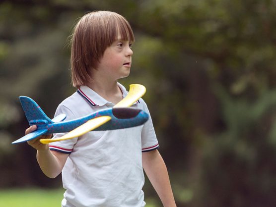 Junge mit Down-Syndrom spielt mit Flugzeug