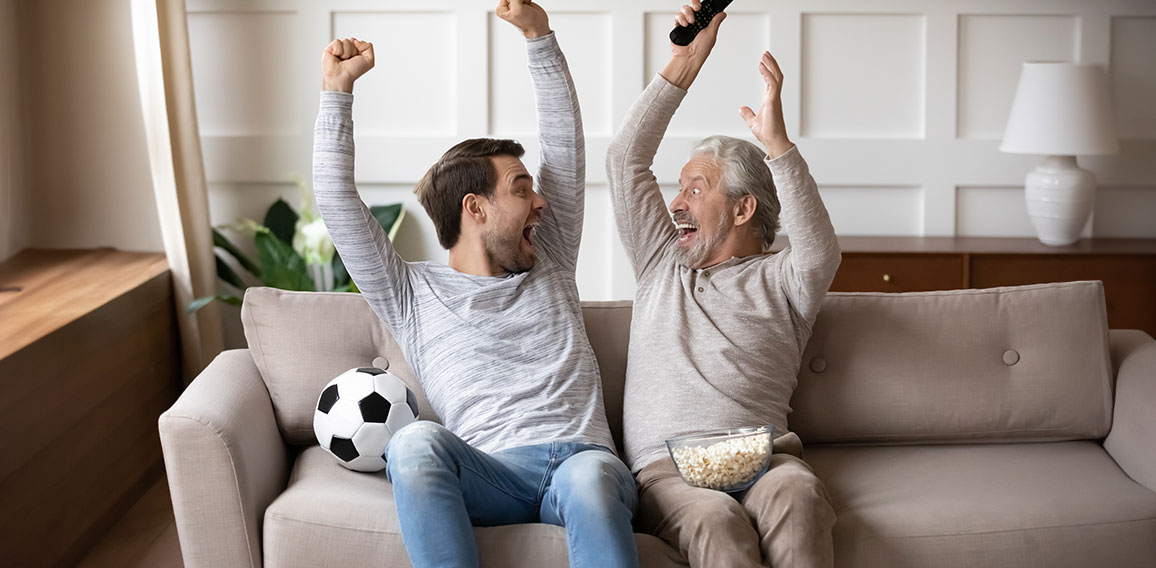 Vater und Sohn auf Couch jubeln über Tor