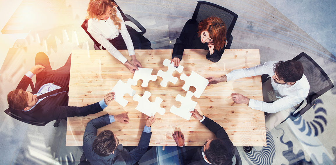 Kolleginnen und Kollegen verbinden Puzzleteile in Büro