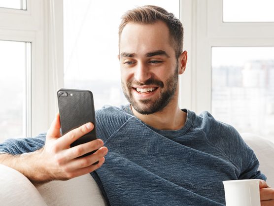 Mann blickt lächelnd auf Smartphone