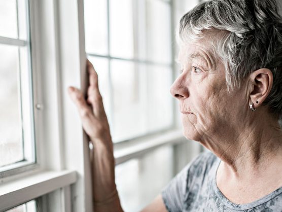 Traurige Seniorin sieht aus Fenster