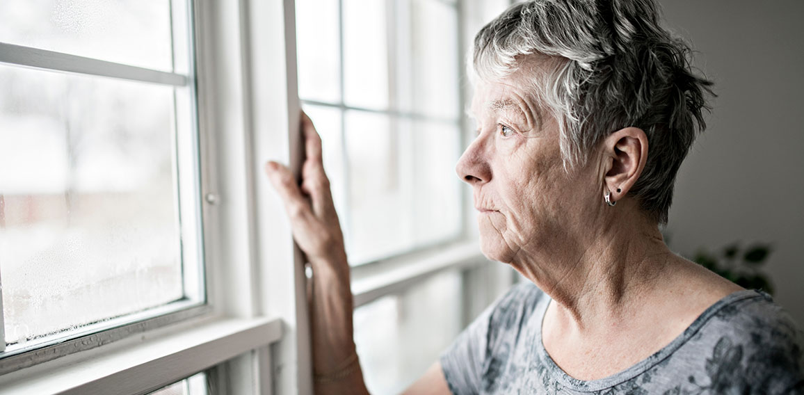 Traurige Seniorin sieht aus Fenster