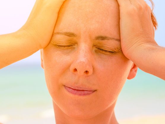 Frau mit Kopfschmerzen an Strand