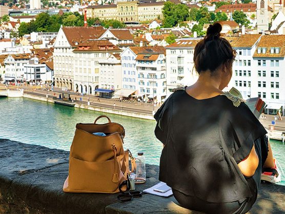 Frau sitzt auf mauer mit Blick auf Zürich