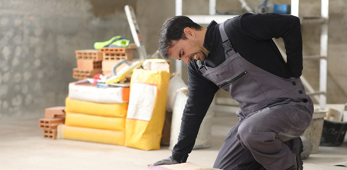 Handwerker auf Baustelle mit Rückenschmerzen