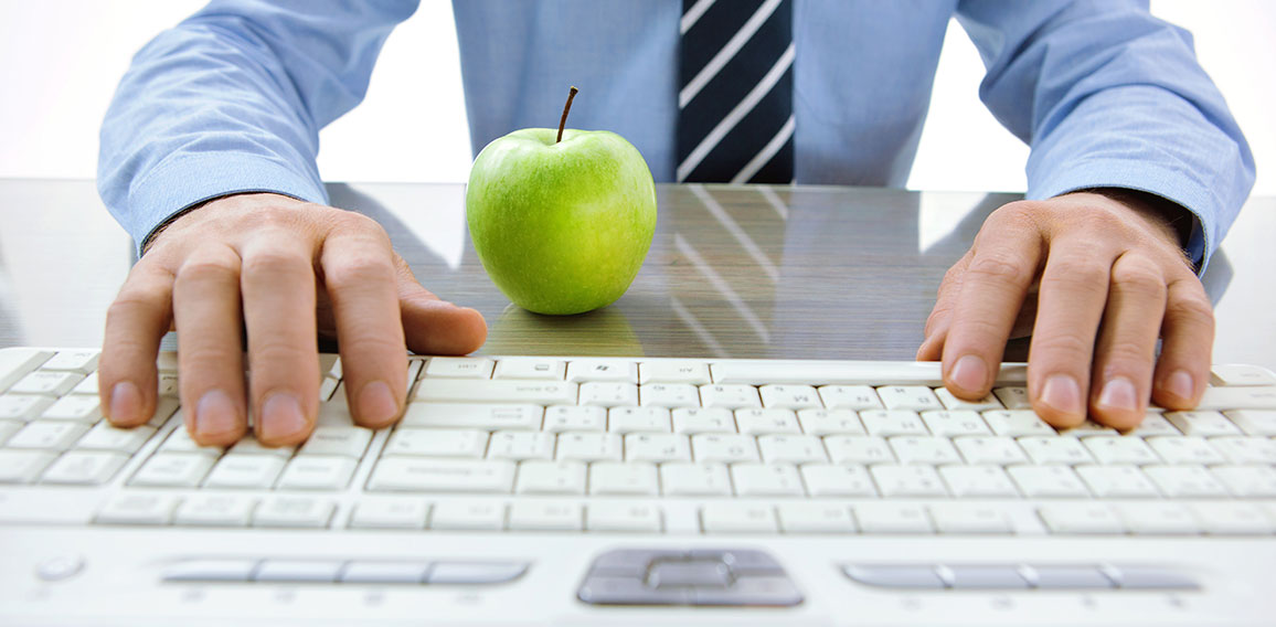 Anzugträger vor Tastatur und Apfel