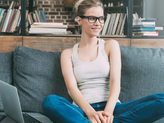 Junge Frau mit Laptop auf Sofa