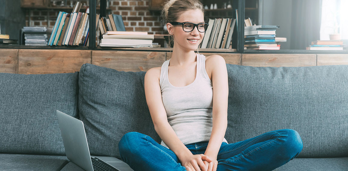 Junge Frau mit Laptop auf Sofa