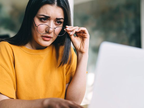 Frau blickt skeptisch auf Laptop