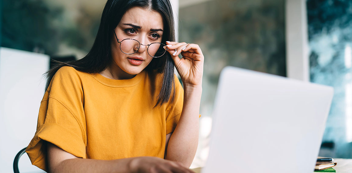 Frau blickt skeptisch auf Laptop