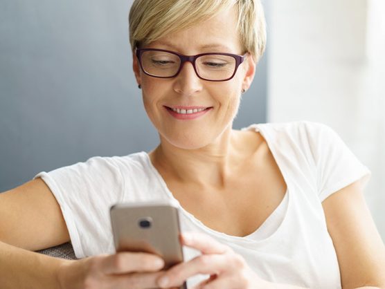 Frau lächelt mit Blick auf Smartphone