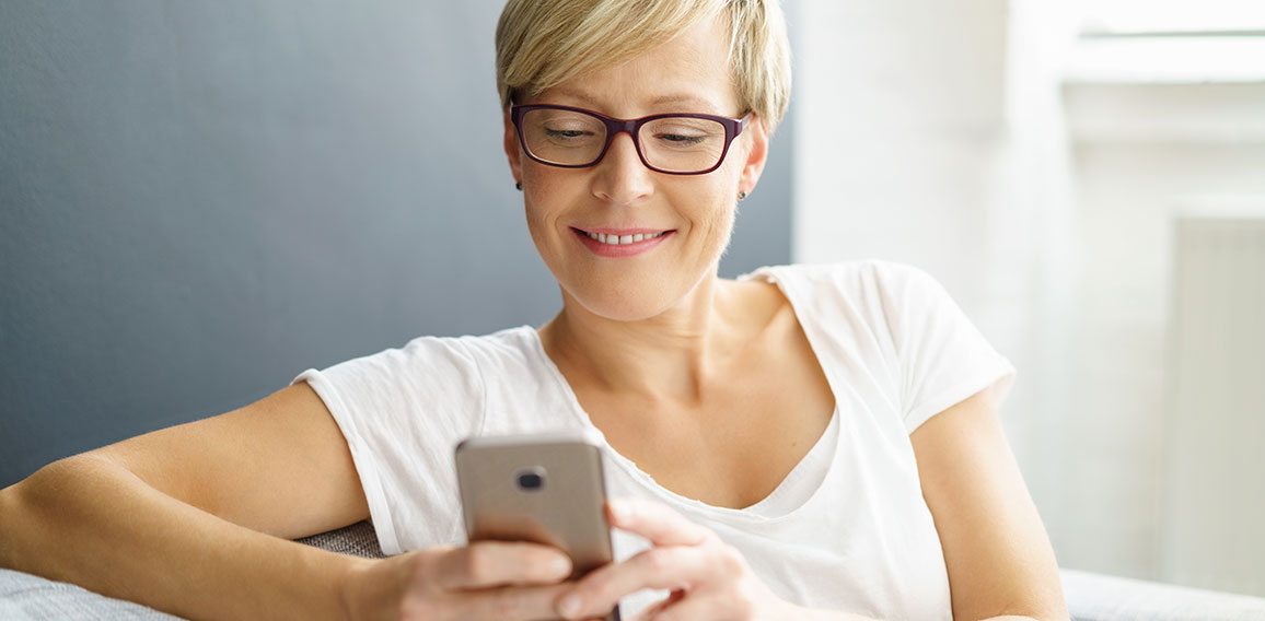 Frau lächelt mit Blick auf Smartphone