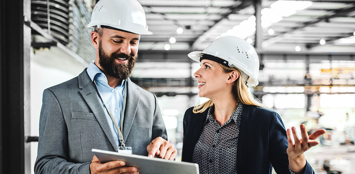 A portrait of an industrial man and woman engineer with tablet in a factory, working.