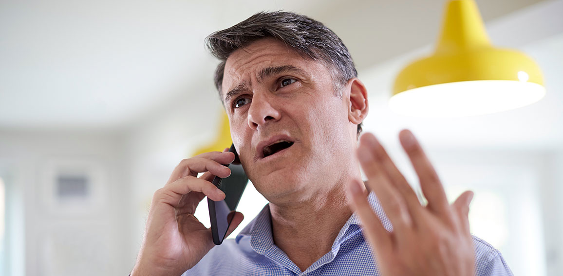 Frustrated Mature Man Receiving Sales Call At Home