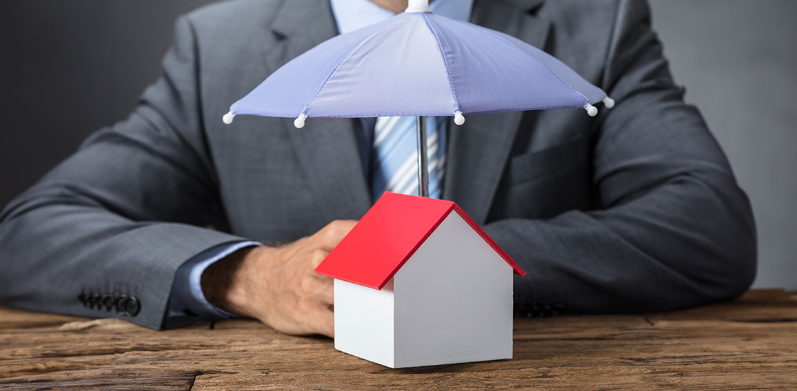 Businessman Protecting House Model With Umbrella