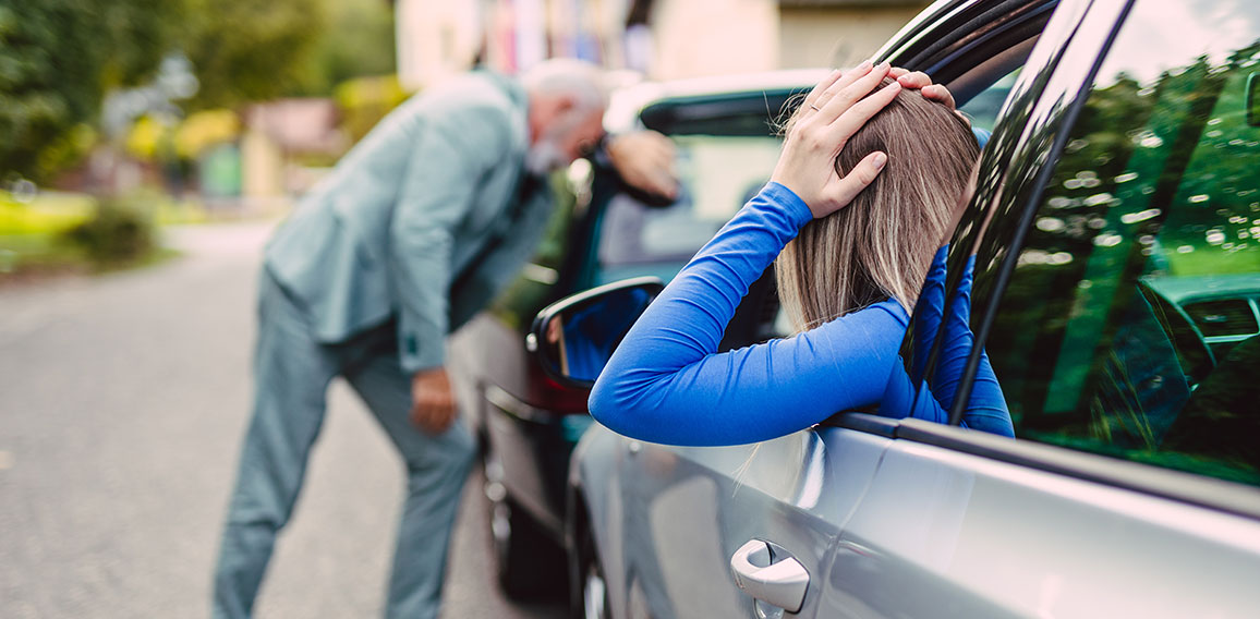 Senior man and young woman arguing after car crash.