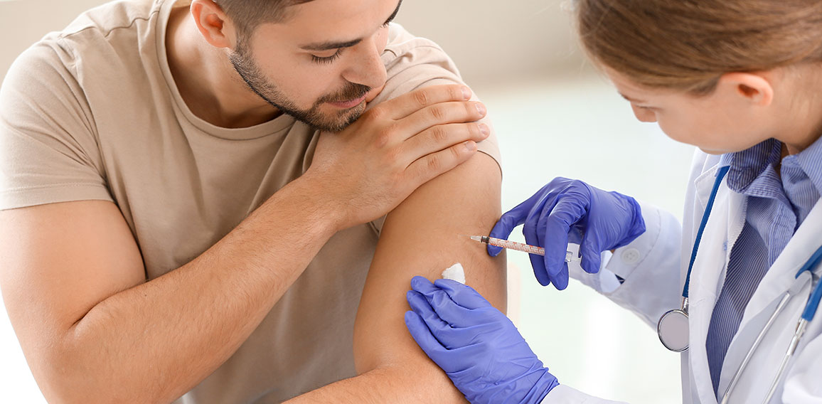 Doctor vaccinating young man in clinic