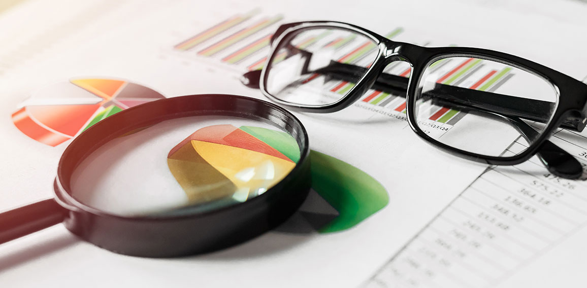 Business reports and a magnifying glass with glasses on table office. Concept of data analysis, investment planning, business analytics.