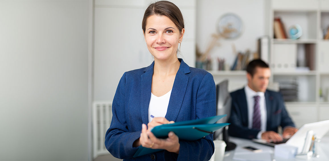 Smiling female business assistant noting tasks on clipboard