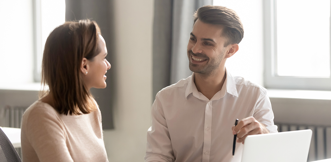 Male and female colleagues talking working together sit at desk