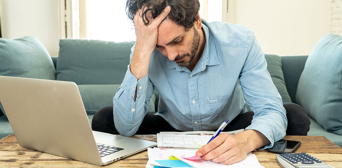 angry man paying bills as home with laptop and calculator