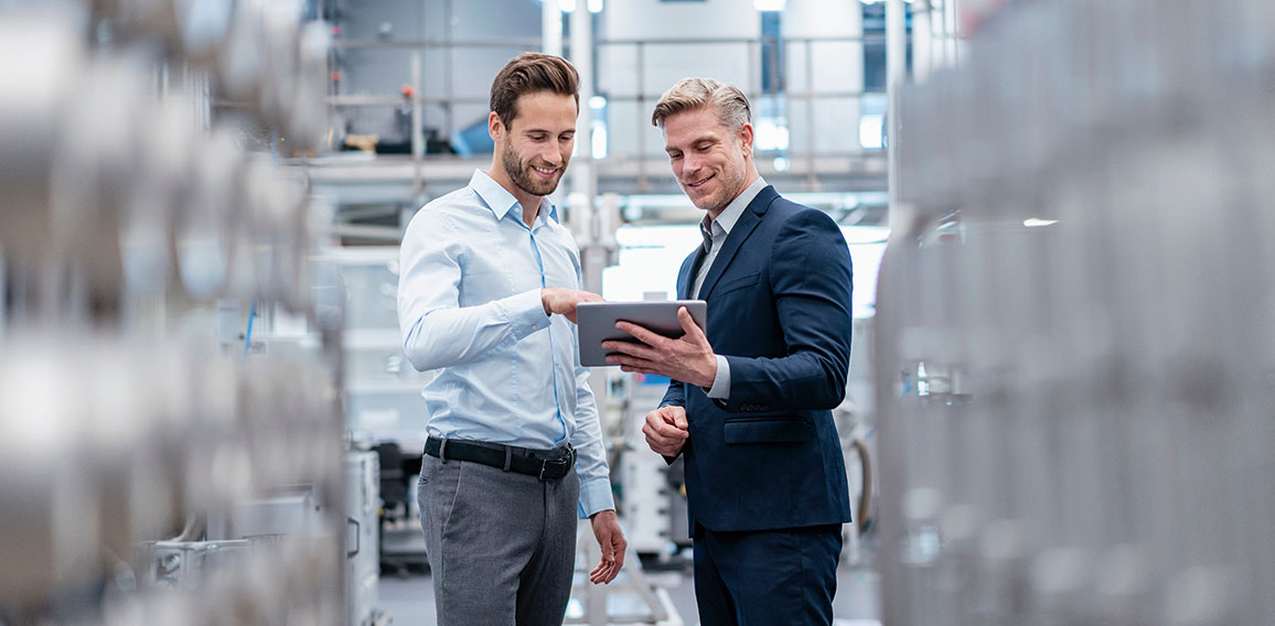 Two businessmen with tablet talking in a modern factory