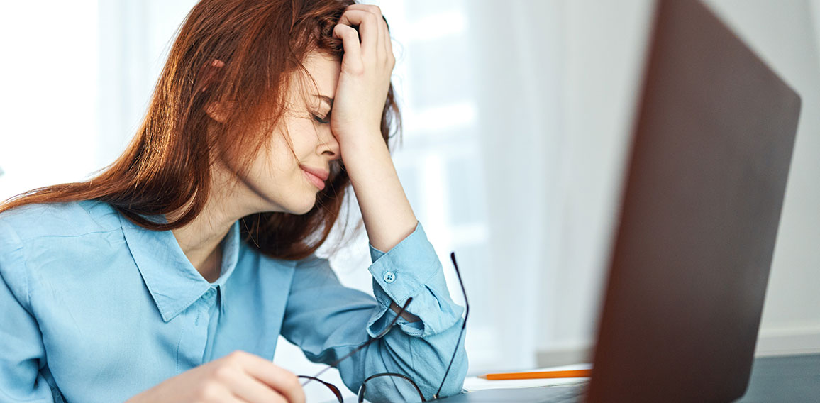 tired woman sitting at a table in front of a laptop work dissatisfaction