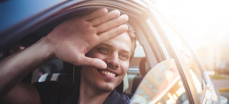 Say hello. Close up side portrait of happy caucasian man driving car.