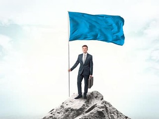 Businessman on the top of a the mountain holding flag