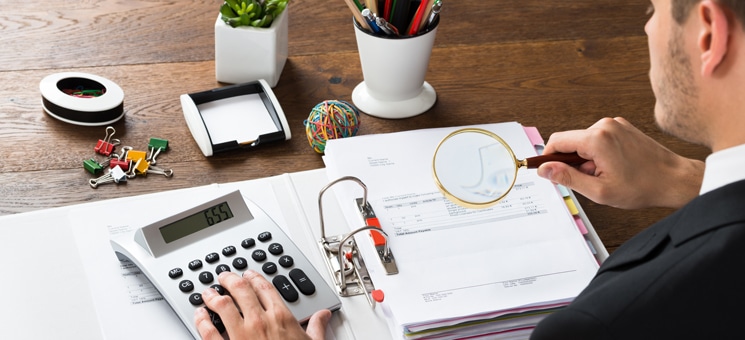 Businessman Inspecting Invoice At Desk