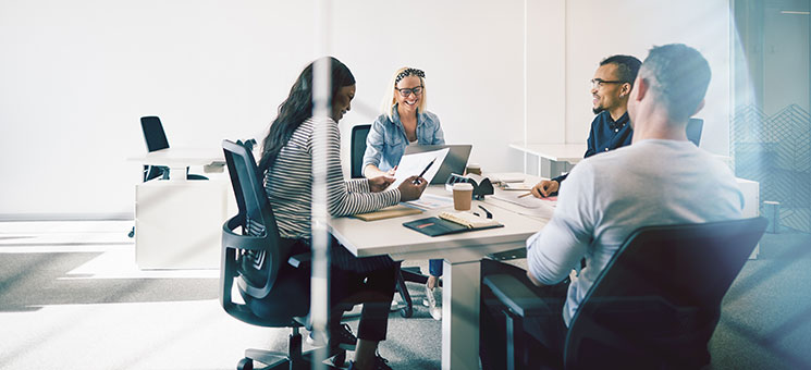 Smiling colleagues meeting together inside of a glass walled off