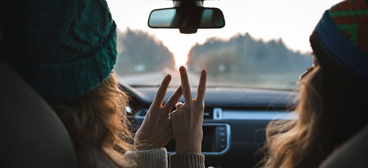 two friends or sisters travelling by car, showing peace sign