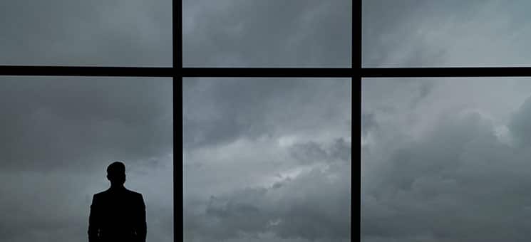 The man with suitcase standing near the big windows in the busin