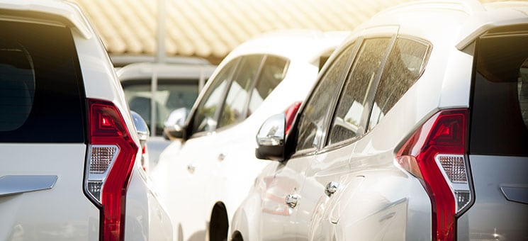 Many white car stop in parking lot outdoor on day.