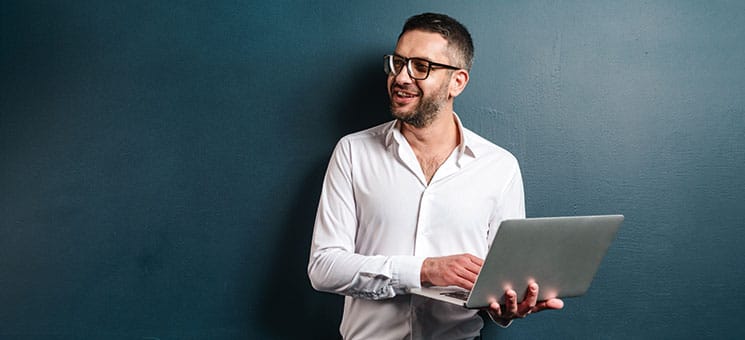 Happy man wearing glasses using laptop computer.