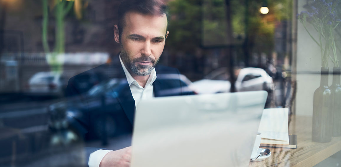 Handsome businessman working on laptop and sitting in cafe