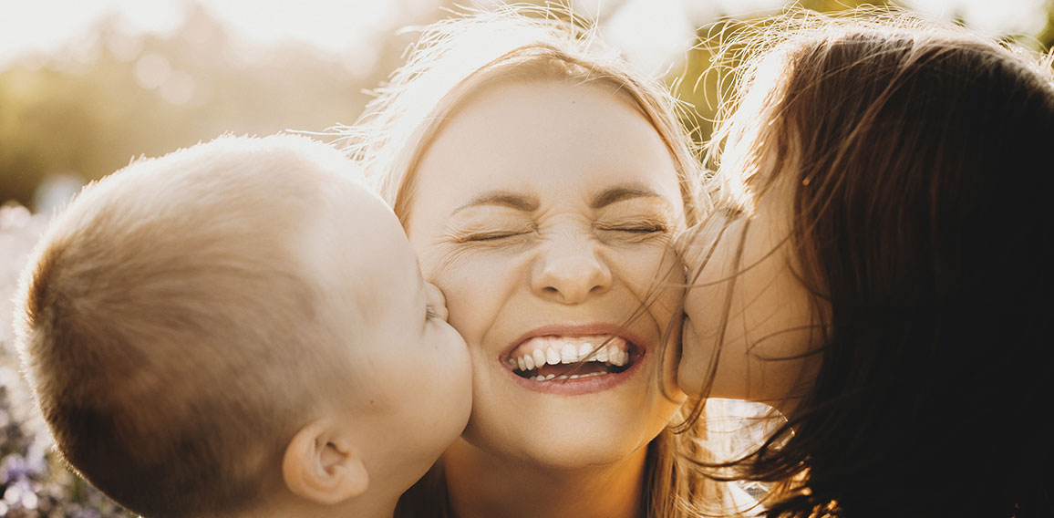 Close up portrait of lovely young mother laughing with closed ey