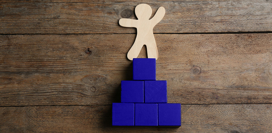 Human figure and pyramid on wooden background, flat lay. Career