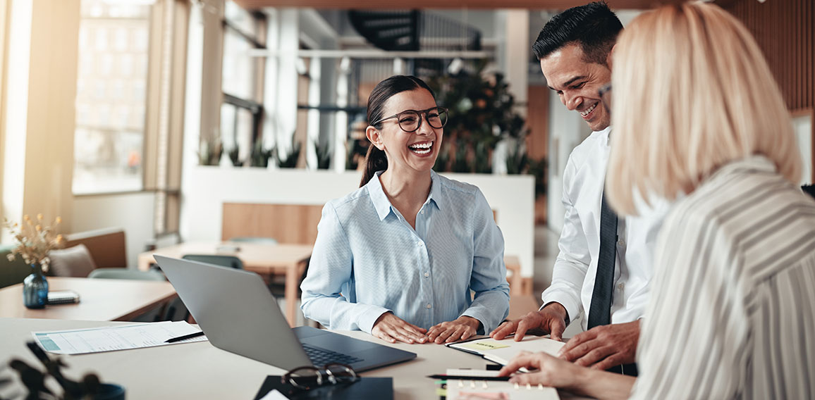 Businesspeople laughing while working at an office table