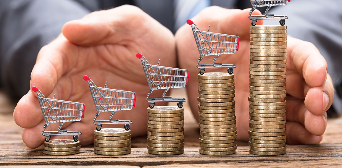 Businessman Protecting Shopping Carts On Stacked Coins