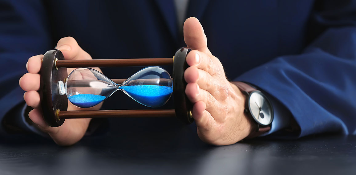 Man holding hourglass over table. Time management concept