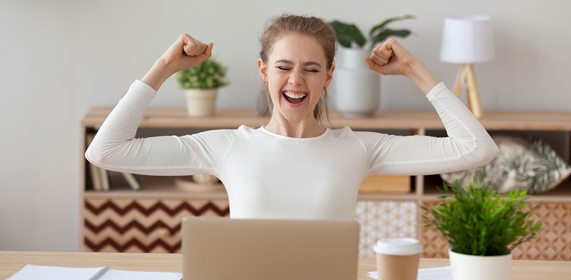 Excited woman feels happy sitting at the desk