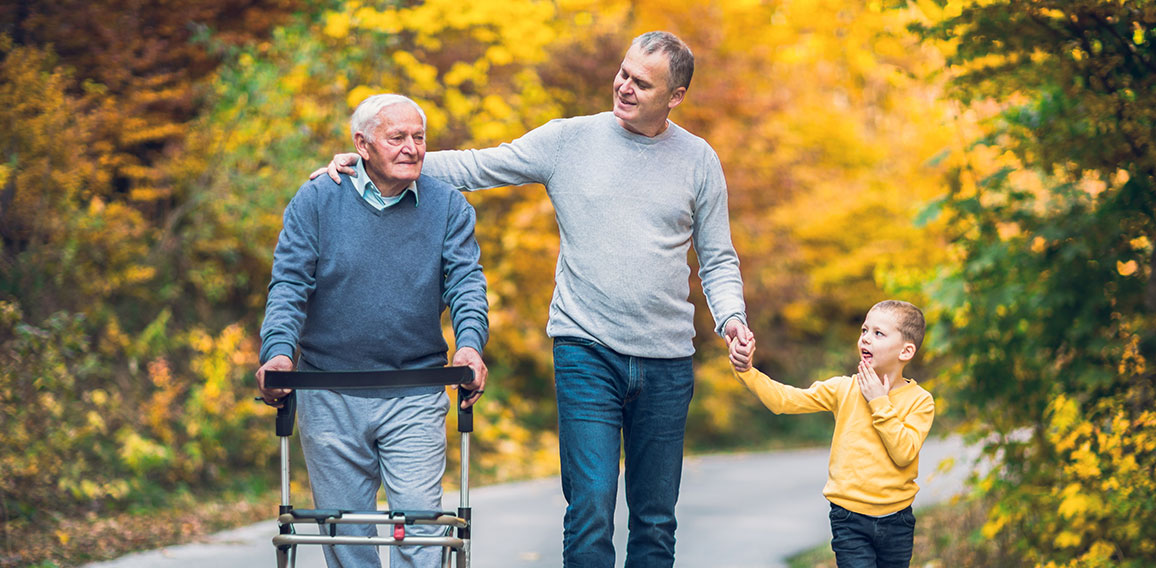 Elderly father adult son and grandson out for a walk in the park