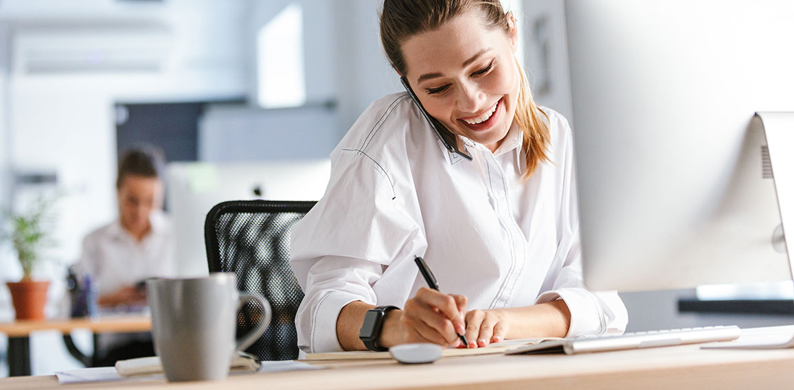 Cheerful young businesswoman sitting at her workplace